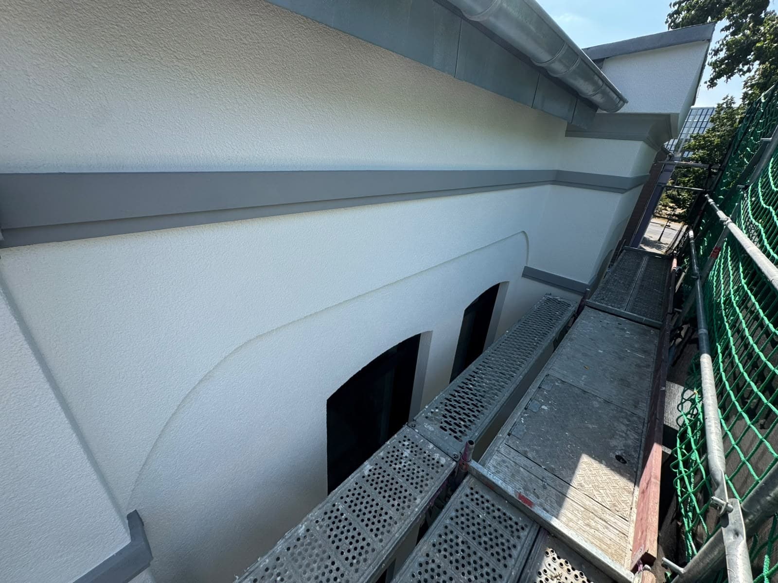 Lange Fassade mit abgesetzten Bändern und Rundbogenöffnungen während der Sanierung